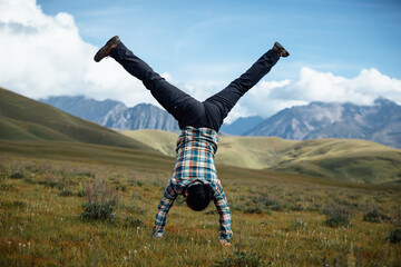 Woman hiker doing a handstand on high altitude mountain top grassland