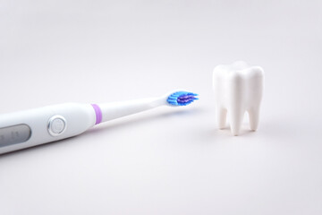 Modern electric ultrasonic toothbrush with rechargeable battery on a gray surface.