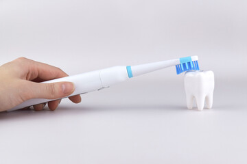 Modern electric ultrasonic toothbrush with rechargeable battery on a gray surface.