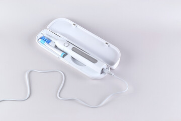 Modern electric ultrasonic toothbrush with rechargeable battery on a gray surface.