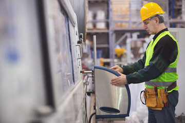 Senior adult operating a machine in factory