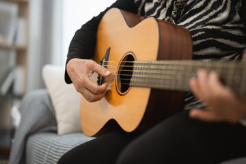 Fototapeta premium Close-Up of Person Playing Acoustic Guitar in Cozy Living Room Setting with Soft Lighting and Comfortable Atmosphere