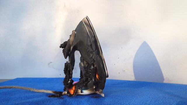 Electrical Short Circuit. Fire socket of electricity plug switch. Burning electric iron. Electric iron in fire. Short circuit in Overloaded. Smoke Burned electric iron. Burning household appliance.