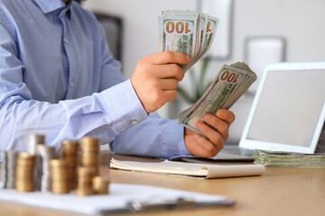 Businessman counting money in office, closeup. Wealth concept
