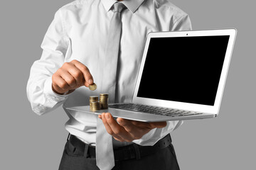 Businessman with laptop and money on grey background, closeup