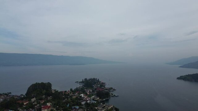 Beautiful 4K aerial footage of Parapat Harbor at Lake Toba, North Sumatra, Indonesia. Captures the peaceful morning atmosphere with calm lake water, boats, and scenic hills