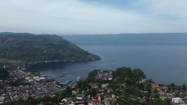 Beautiful 4K aerial footage of Parapat Harbor at Lake Toba, North Sumatra, Indonesia. Captures the peaceful morning atmosphere with calm lake water, boats, and scenic hills