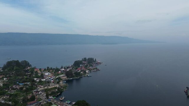 Beautiful 4K aerial footage of Parapat Harbor at Lake Toba, North Sumatra, Indonesia. Captures the peaceful morning atmosphere with calm lake water, boats, and scenic hills
