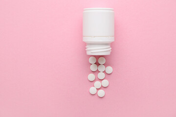Jar with white pills on pink background