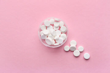 Container with white pills on pink background