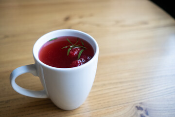 Raspberry tea in a white mug on a wooden table.