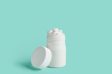 Jar with white pills on turquoise background