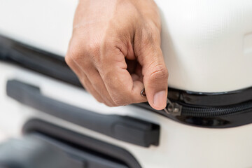 Zipping Up and Finalizing Luggage. A close-up of a hand zipping a suitcase, ready for the travel adventure ahead.