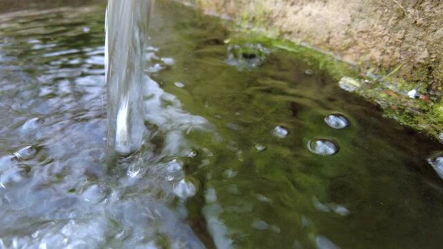 Water falling into small basin creating bubbles and ripples