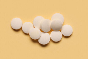 Many white pills on yellow background