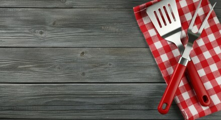 Obraz premium A rustic wooden table serves as a backdrop for the neatly laid out red checkered napkin on the right side of the table