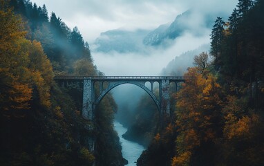 Fototapeta premium Scenic bridge over a misty river between autumn-colored trees and mountains