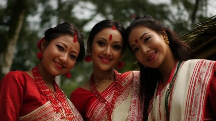 Three Assamese women in traditional mekhela chador smiling outdoors, celebrating culture and friendship – diversity, tradition, and ethnic identity