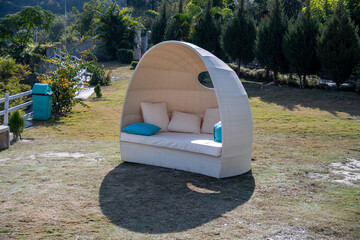 A dome sofa adorned with white and blue cushions is set in the lawn, providing a comfortable seating area. This inviting setup enhances the landscape.