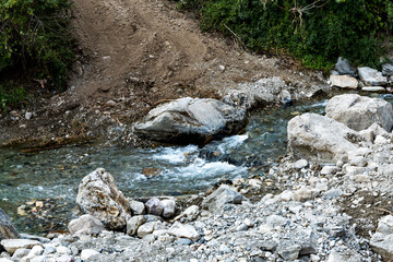 A small river water source flows gracefully among the rocks. This natural feature adds a serene element to the surrounding landscape.
