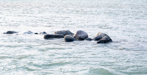 Large stone pebbles and rocks are scattered in the River Ganges in Rishikesh. This natural feature enhances the river's beauty and charm.