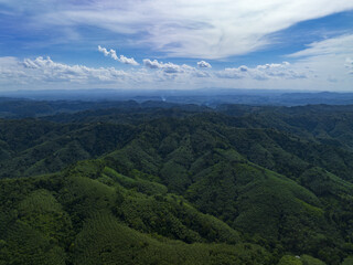 Fototapeta premium Aerial view of lush green forest and mountains under cloudy sky , beautiful countryside of Thailand. sunny afternoon. wonderful springtime landscape in mountains.