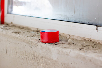A roll of bright red tape is resting on a window sill above