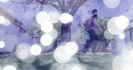 Father and son kicking soccer ball on grass lawn, showing animated health icon and fitness chart - Powered by Adobe