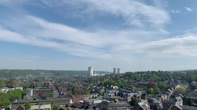 Panoramic, scenic aerial view of Huy city, mountains and chimneys of nuclear power plant. Airplane is flying above and descending towards Liege airport. View from Fort de Huy. Huy, Belgium