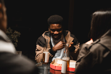 Friends enjoying a late night gathering with food and drinks in a cozy setting