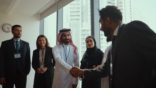 Multicultural businesspeople wearing suits and traditional clothing stand together in a modern office, embodying teamwork and cultural diversity.