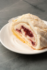 Delicious meringue dessert with cream and cherry filling served on a white plate