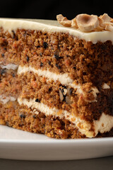 Deliciously layered carrot cake with cream cheese frosting and chopped nuts displayed on a white plate