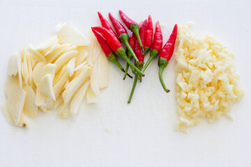 Fresh garlic slices, red chili peppers, and minced garlic on a white background, perfect for culinary, cooking, and food ingredient concepts