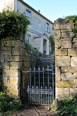 Gated entrance and stone wall of an old house on a street in an English village © 1000 Words