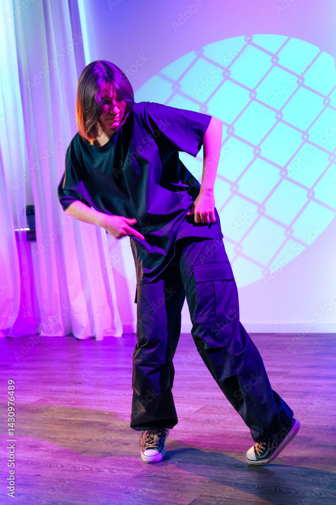 Poster dancer performing an expressive routine in a contemporary studio space with colorful lighting and sh