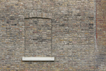 A brick wall with a window bricked up