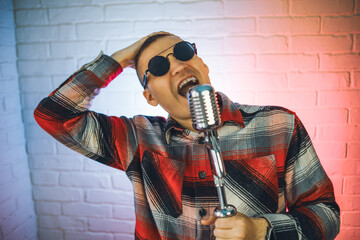A man wearing a plaid shirt enthusiastically sings into a microphone, showcasing his passion for...