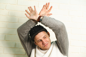 A man wearing a black cap and a gray sweater is captured in motion, dancing gracefully with fluid...