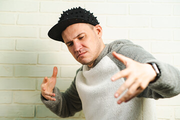 A man wearing a black cap and a gray sweater is captured in motion, dancing gracefully with fluid...