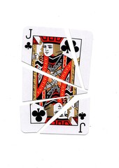 A playing card in the suit of clubs cut into sharp pieces.