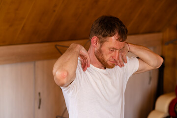 A professional sportsman in a white shirt is standing, holding his hands on his head as he performs...
