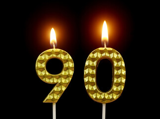 Burning gold birthday candles isolated on black background, number 90.