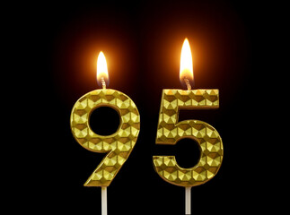 Burning golden birthday candles isolated on black background, number 95.	