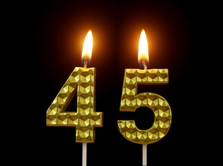 Burning golden birthday candles isolated on black background, number 45.	