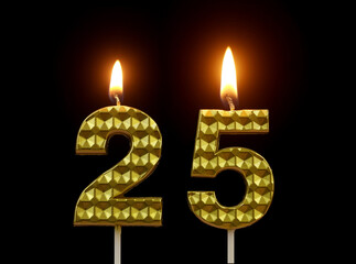 Burning golden birthday candles isolated on black background, number 25.	