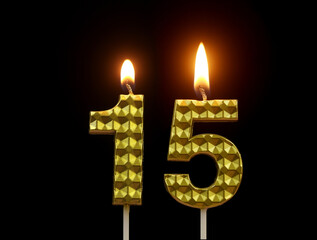 Burning golden birthday candles isolated on black background, number 15.	