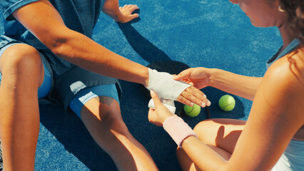 Bandage, hands and help for athlete with injury, sports and player with broken bones and fitness. Outdoor, people and accident at tennis court, above and woman with first aid for inflammation © peopleimages.com