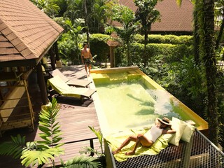 Sunbathers enjoy leisure time by beautiful pool surrounded by vibrant greenery. A tranquil escape...