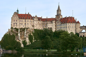 Obraz premium Sigmaringen Castle Perched on Rugged Cliff Above Tranquil Danube: Historic Hohenzollern Residence Showcases Medieval Architecture and Royal Collections in Picturesque Baden-Wurttemberg Landscape